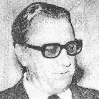Leon Łoś, mężczyzna w ciemnych okularch z grubymi oprawkami. Ubrany w garnutur.