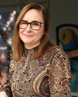 Agnieszka Klimas, uśmiechnięta kobieta w modnych okularach i wzorzystej brązowej bluzce 