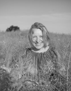 czarno-biała fotografia uśmiechniętej szeroko blondynki w krótkich włosach w polu dojrzałego rzepaku