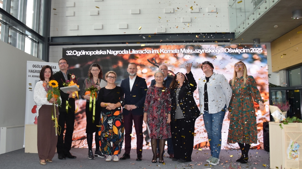 Laureaci nagrody stoją na scenie, trzymają kwiaty, wokół nich lata złote confetti.