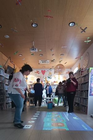 Kilka bibliotekarzy patrzy na podłogę, na której wyświetla się gra