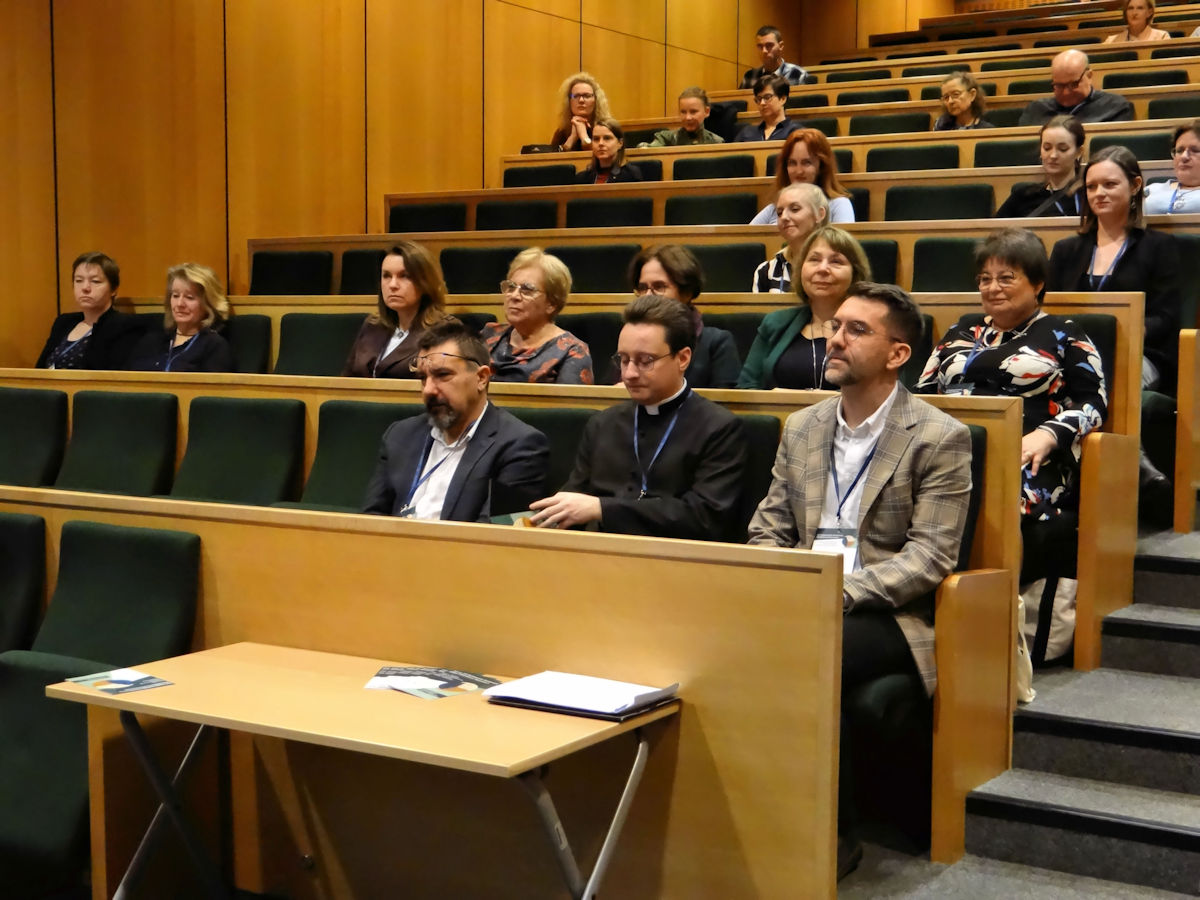 sala wykładowa, kilka osób siedzy w drewnianych ławach