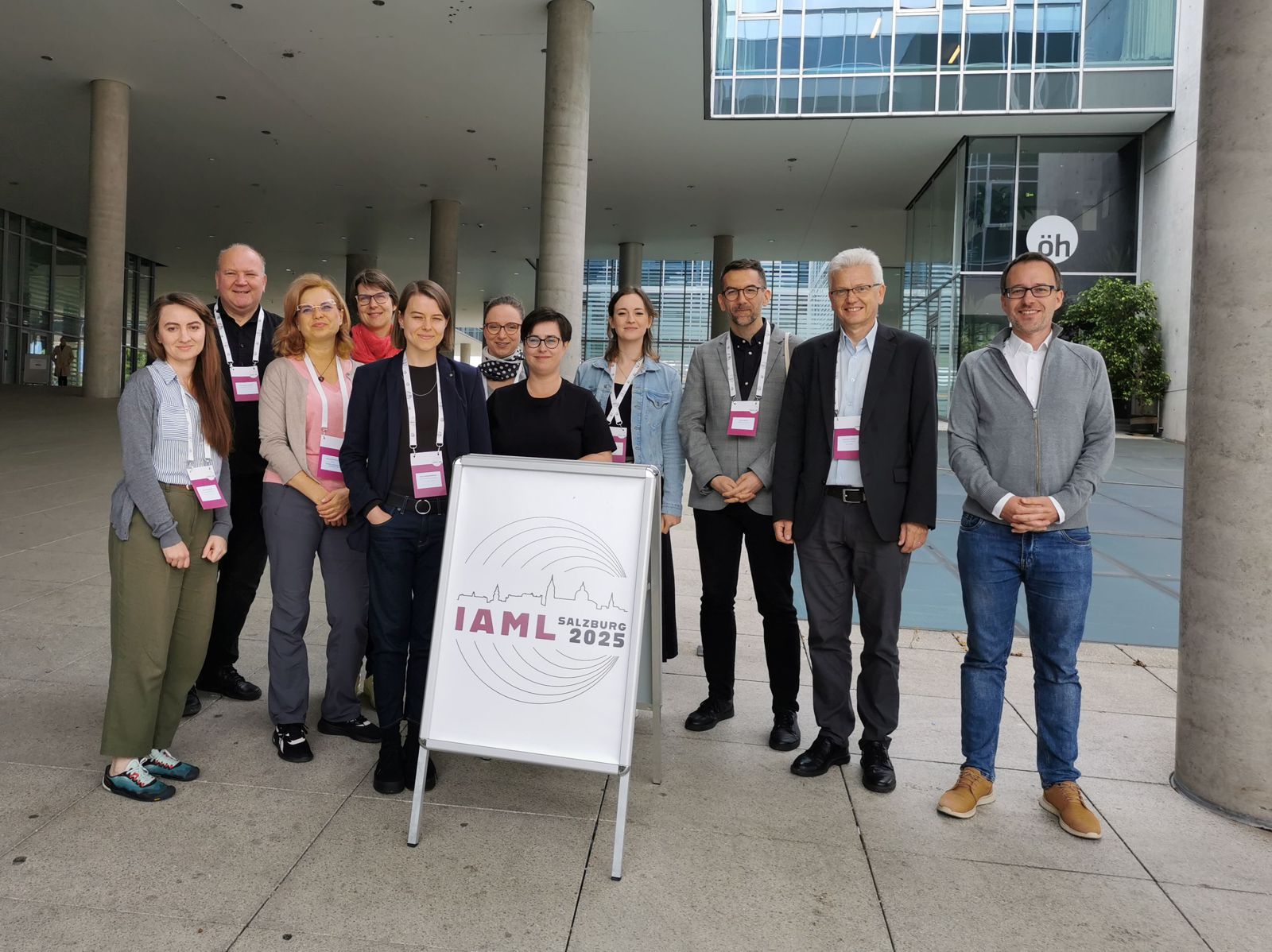 Grupa bibliotekarzy stoi przy potykaczu z nazwą konferencji